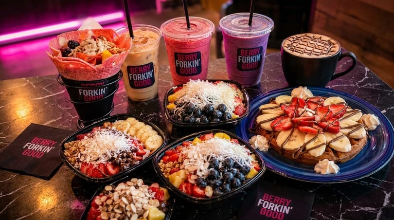 A table laden with Berry Forkin' Good acai bowls, smoothies, a waffle, and a coffee.